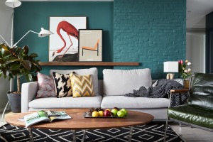 蓝绿色的沙发背景墙使整个空间更加时尚前卫，砖体外露的设计成为了整个客厅的亮点。木质的茶几面与不锈钢的