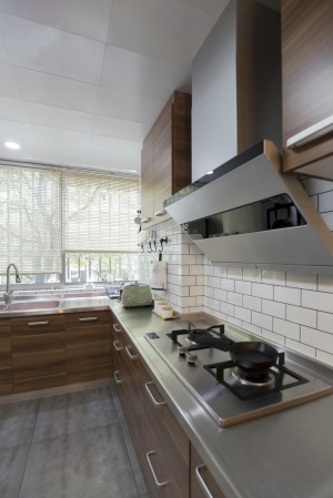 【厨房装修效果图】通透干净的百叶窗帘，白色的墙砖与木质的柜门搭配，使得厨房的空间宽敞明亮。