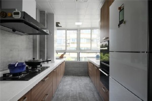 【厨房】厨房通畅明亮，地面和墙壁采用灰色砖，增加了和谐感，搭配木质橱柜与白色的操作台面，整个空间都充