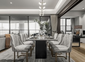 客餐厅的布局，布置大理石台面的餐桌，金属架的餐桌椅，灰色与灰白色的布艺坐垫餐椅，整体空间显得淡雅而舒