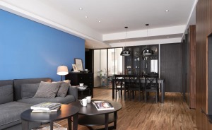客厅以蓝色为背景，搭配上深灰色柔软沙发，就这样简单而舒适的空间打造出来了