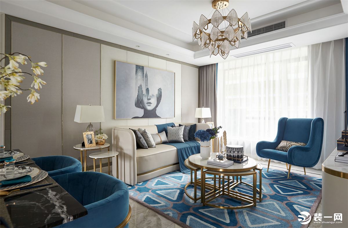 地面铺上蓝白三角形线条的地毯，布置优雅的茶几、凳子与边几，一张造型优雅的沙发。背景墙的画框设计为空间