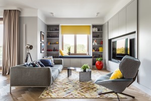 浅灰色的布艺沙发搭配条纹地毯，沙发旁的书架设计了一个一体化的坐塌，舒适放松。
