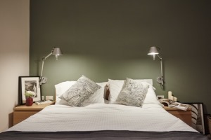 卧室抹茶绿的背景墙，床头对称的小灯，照耀在床上，感受明亮，躺在床上柔软舒适。