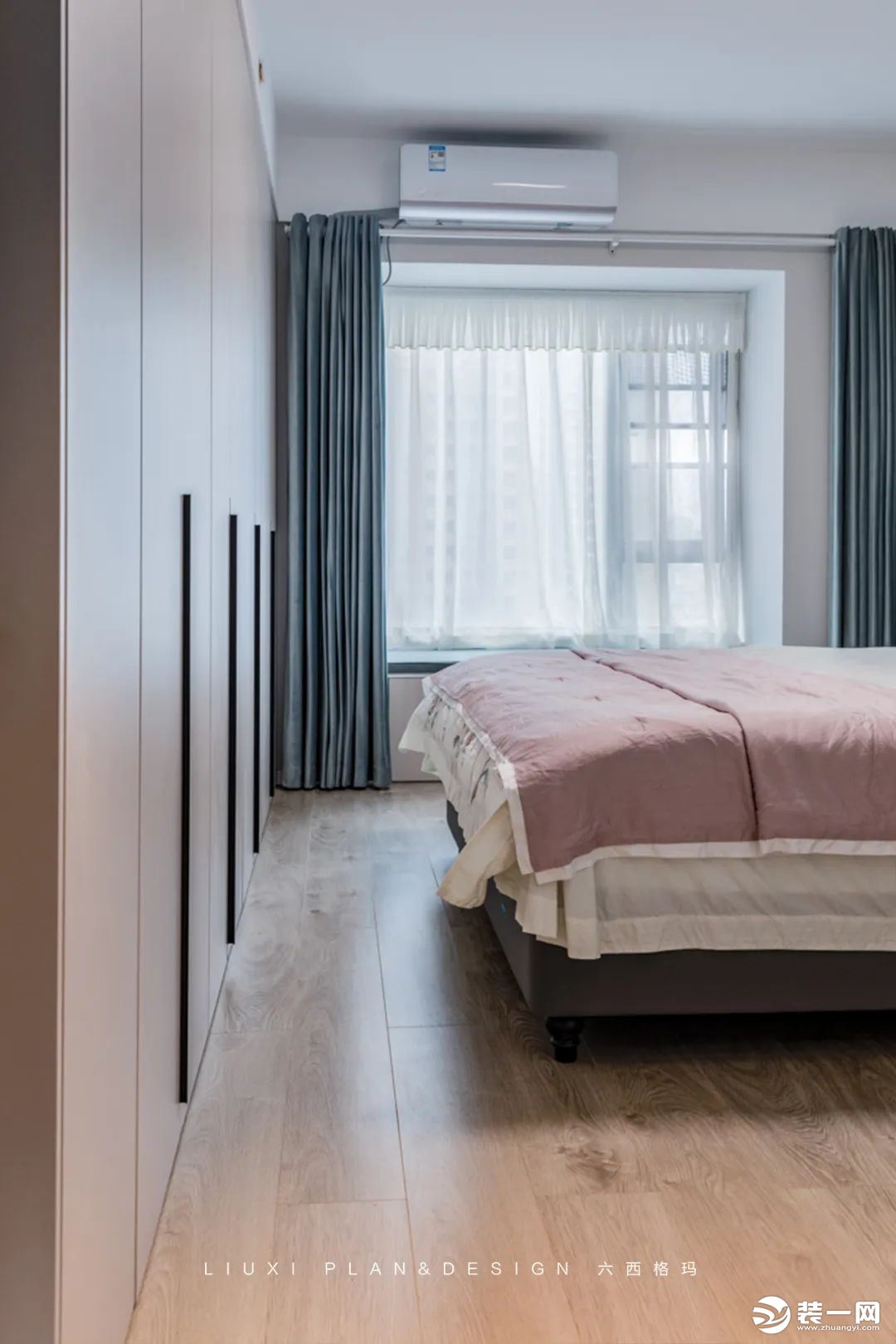 主卧设计用恬淡的粉+灰蓝配色，为空间注入恰好的居住温度。床尾做了一排通顶的衣柜，搭配1米长的黑色长条
