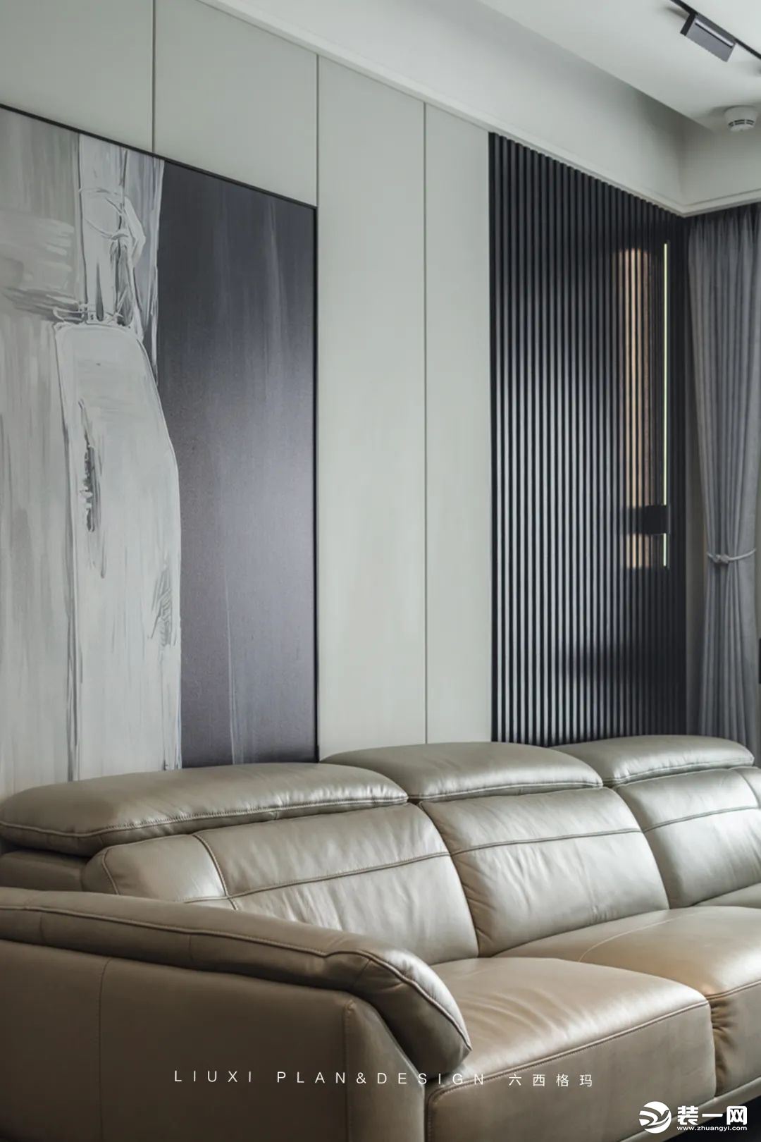 沙发背景墙由墙板+装饰画+长城板以及线性灯组成，冰川灰墙板硬包造型，加上一幅装饰画，营造出简约大方的