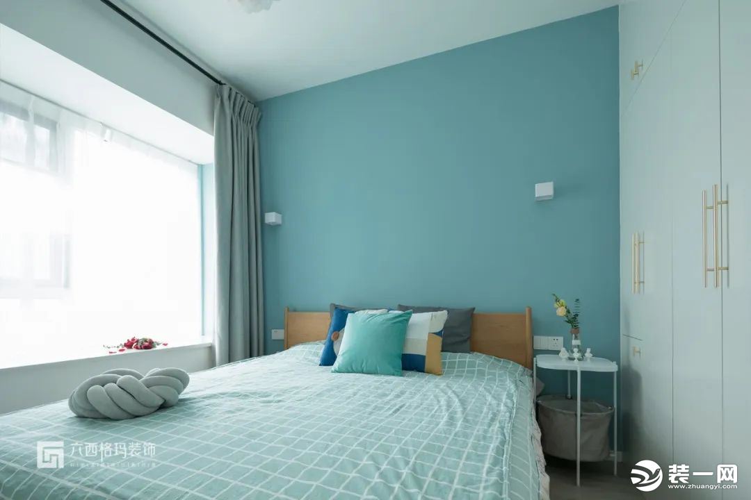 木質的床，藍色的背景墻搭配兩盞方盒白色壁燈，清爽、利落。白色通頂大衣柜+黃銅拉手，簡約優雅視感~