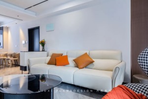 家具的摆布遵循简约的现代主义。奶油色沙发+橙黄色抱枕，拉升着空间的温馨感和舒适度。角落处摆放着不过时