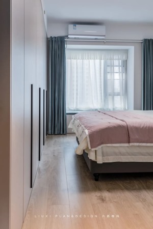 主卧设计用恬淡的粉+灰蓝配色，为空间注入恰好的居住温度。床尾做了一排通顶的衣柜，搭配1米长的黑色长条