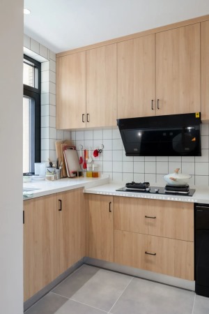 厨房灰色地砖搭配小白墙砖，结合木色橱柜搭配黑色拉手以及白色台面，显得简单又干净