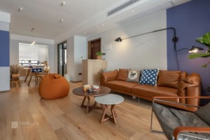 复古的焦糖咖色皮沙发传递着一种温暖感，地上随意摆放的懒人沙发，为客厅增添了慵懒的氛围。深木色和水磨石