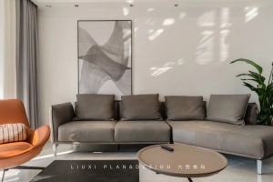 黑灰色茶几组成“方圆”CP，简洁、明快，与灰色的沙发和单幅抽象装饰画形成了一种和谐的匹配。角落处的绿