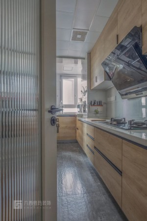 厨房以网红款的长虹玻璃门，搭配灰黑色地砖，显得简约端庄。木色的橱柜，白色的操作台面，展现出简约风的美