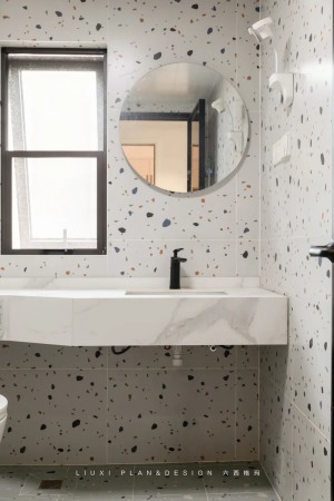 卫生间墙地面铺贴了不同颜色的水磨石砖，实现区域的划分；搭配圆形的梳妆镜，塑造出些许的清新感