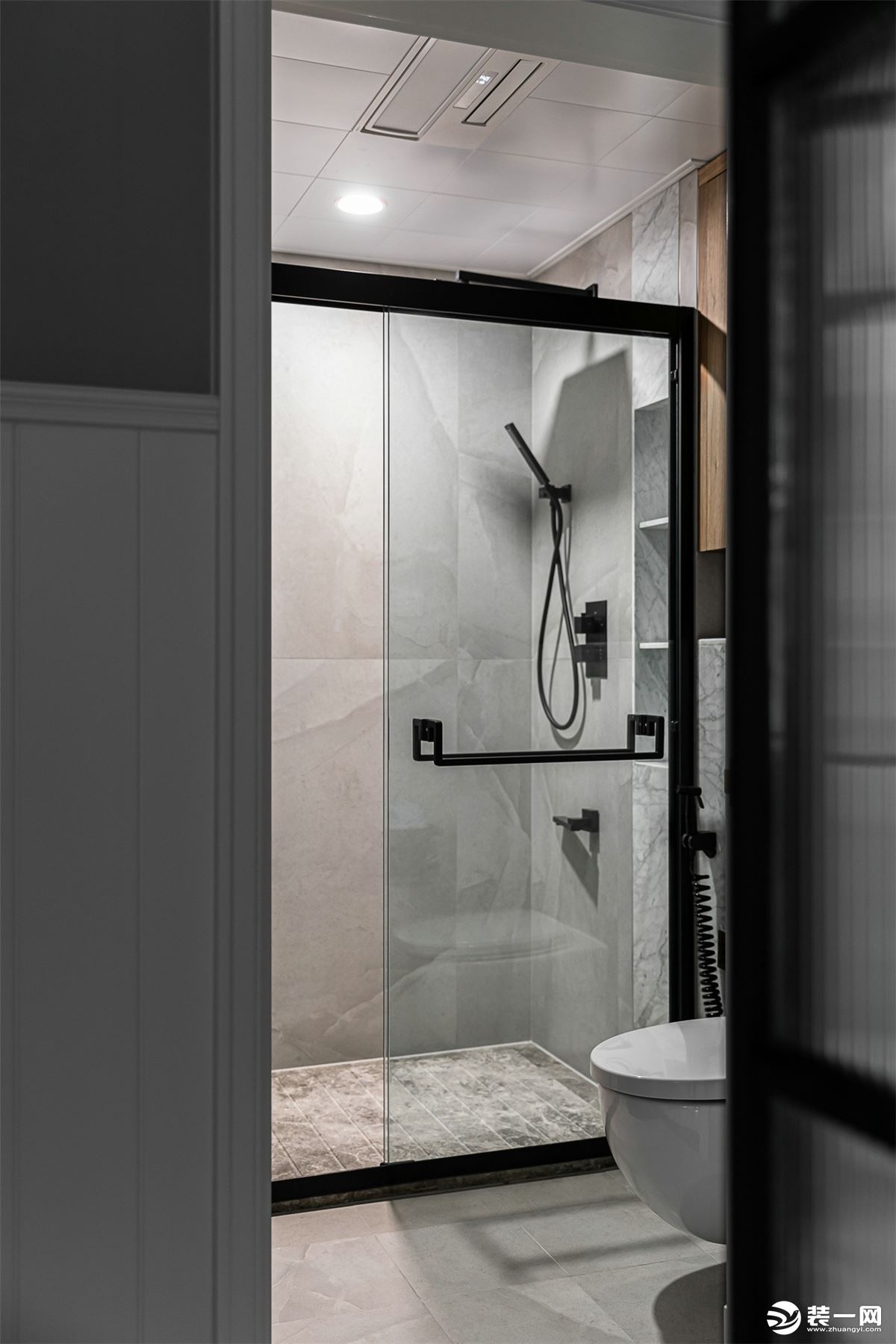 卫生间使用易打理的灰色墙地砖、石材，搭配木色柜体，简约而舒适