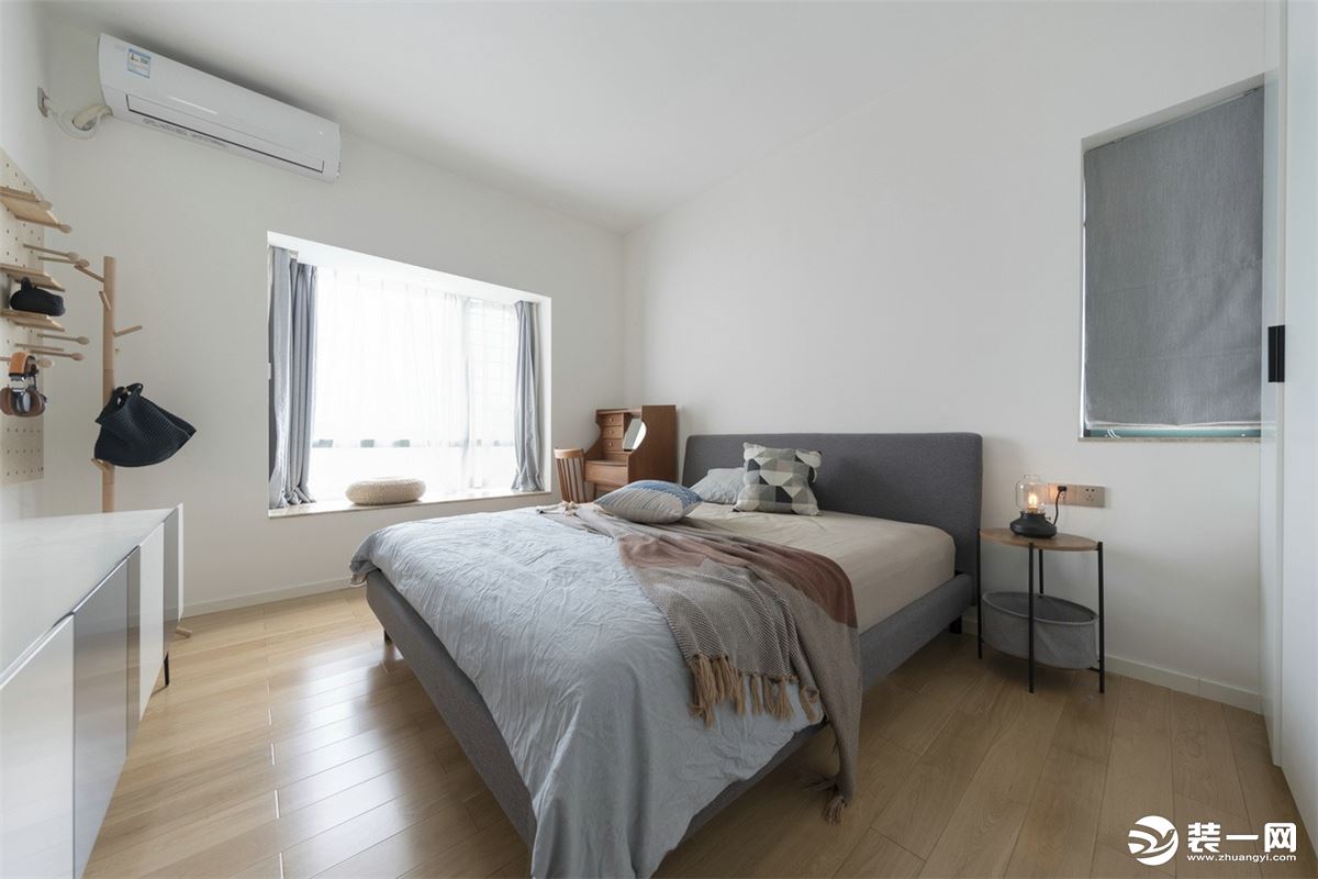 卧室延续简洁干净的基调，原木色的地板、素白色的墙面、暖灰色的家具以及同色系的床品和窗帘，和谐简约又不