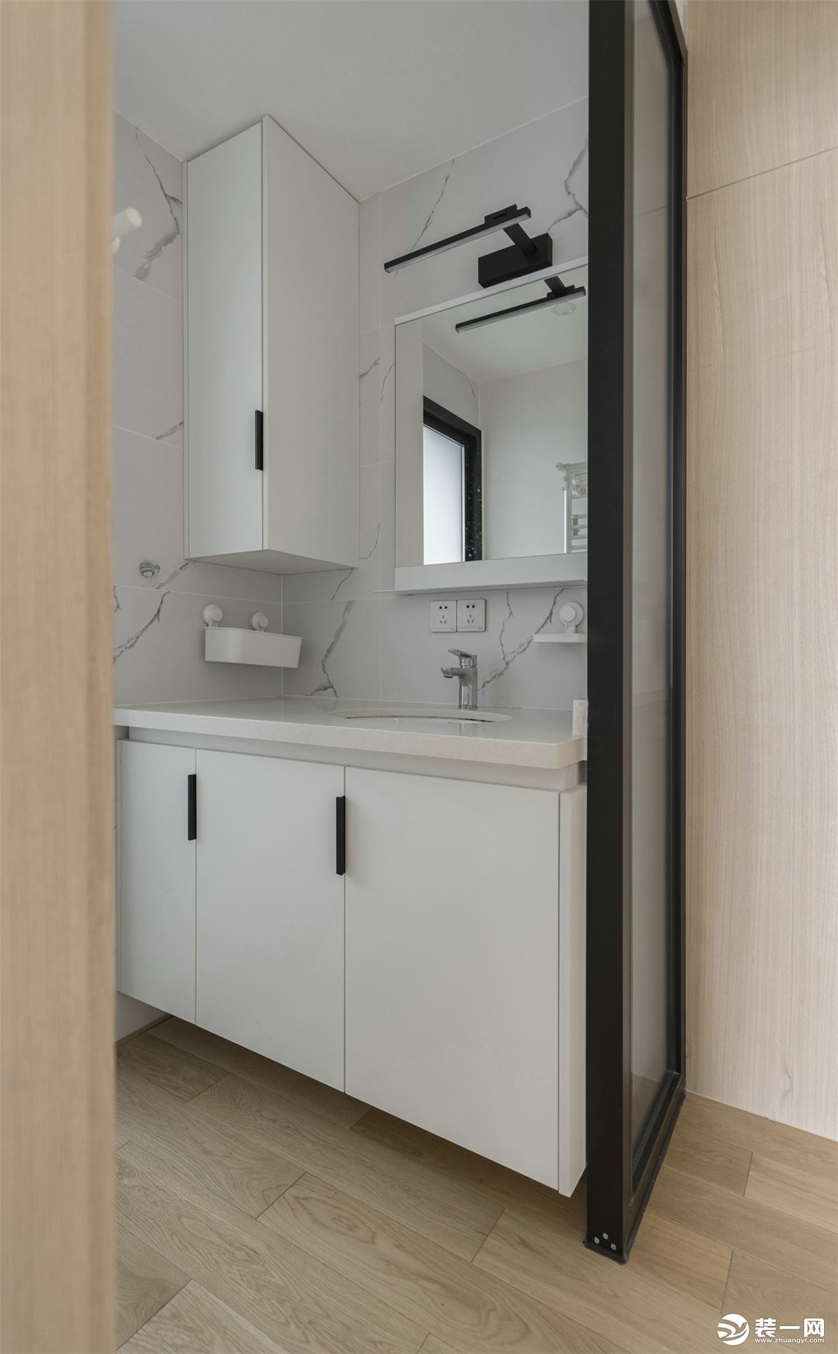 卫生间将洗手台外置，提高了日常使用效率。黑白色调的浴室柜与大理石墙砖的纹理相呼应，视觉上营造了延伸的
