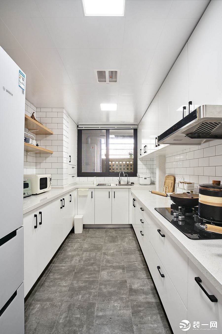 白色的厨房， 视觉上大气整洁。 大理石地砖取代地板， 打理起来更加轻松。 小白砖错落， 黑色橱柜把手