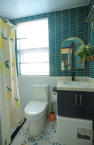 洗手间铺了花砖，墙面用了两种颜色的条形砖分色。洗手台下面是提前预留好的放猫砂盆的空间。柠檬图案的浴帘