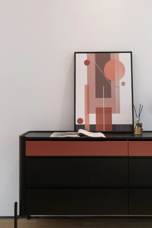 设计师非常注重空间的互动，床尾的置物柜上选择红色抽象几何挂画，与床头的纹理挂画呼应，