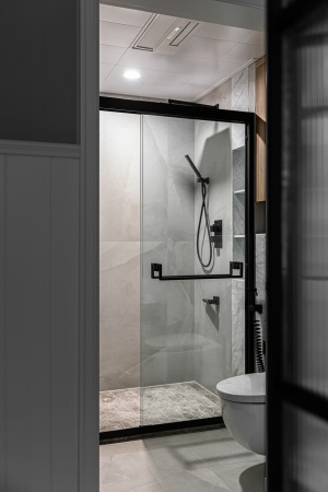 卫生间使用易打理的灰色墙地砖、石材，搭配木色柜体，简约而舒适
