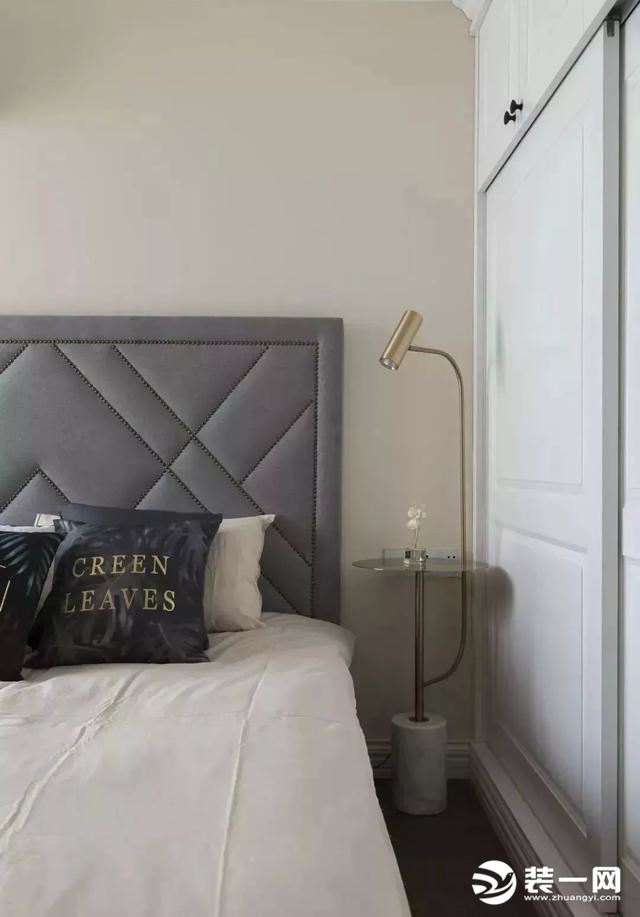 主卧室的床头背景墙是刷成了藕粉色，搭配软包的床头靠背和金属质感带收纳的落地灯，给人一种淡淡的优雅、精