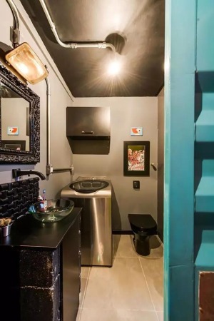 卫生间也被黑色所包围，不锈钢材质的洗衣机的放置让这个空间更加的充实。