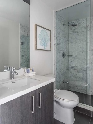 卫生间以深灰色的地砖基础，墙面则是仿大理石质感的设计，淋浴房以外的墙面刷着防水漆，让卫浴空间更加有温