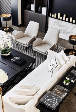 宽大的米白色布艺沙发，地面上还有黑白条纹的地毯，黑白配的空间，布置出舒适优雅的华丽气质