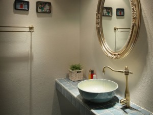 卫生间的墙面使用了比较粗糙的硅藻泥材质形成哑光的效果。复古的圆镜和蓝色纹理砖刚好能够衬托别致的景象。