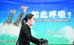 一名戴口罩出行的市民与身后的环保公益广告相映成趣