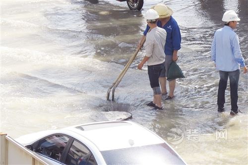 工作人员积极寻找路面出水口排涝